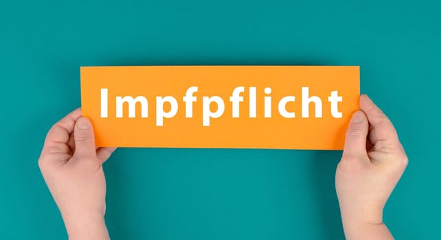 The word mandatory vaccination is standing on the paper, german language, compulsary vaccine, covid-19 regulations