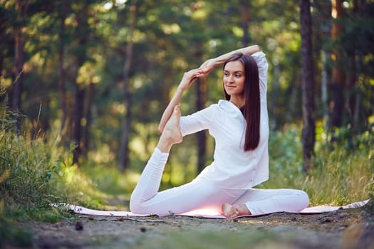 Flexible woman stretching her legs and arms in park