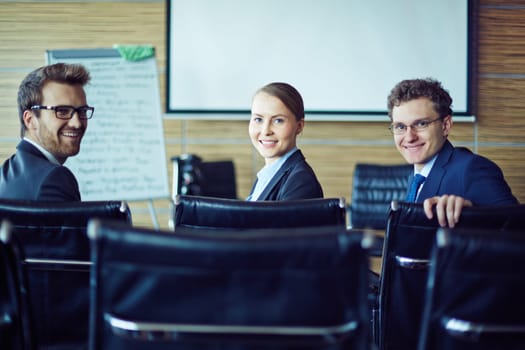 Happy co-workers looking at camera in conference hall