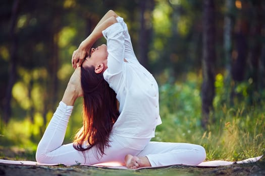 Active young female stretching her body in park