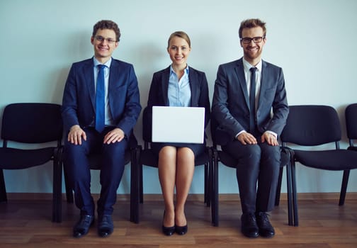 Happy co-workers sitting on chairs along wall