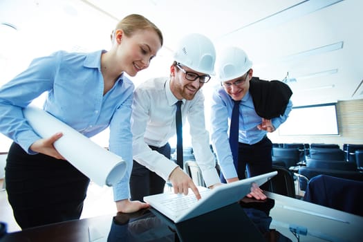 Young architects consulting at meeting and using laptop