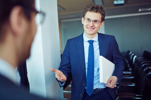 Elegant employee in suit and eyeglasses welcoming business partner