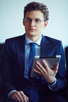 Elegant young businessman holding touchpad