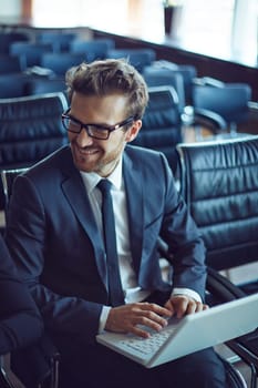 Male employee typing while listening to colleague at meeting