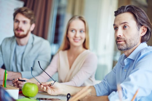 Confident businessman debating with co-worker at meeting