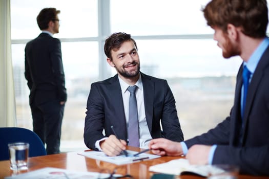 Young man communicating with his colleague in office