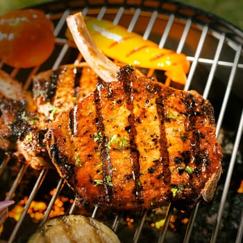 Delicious crispy barbecued marinated and seasoned pork loin cutlets with eggplant and tomato cooking on a grill , close up view of the meat