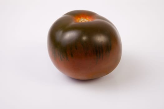 One dark green kumato tomatoe. Isolated over white background