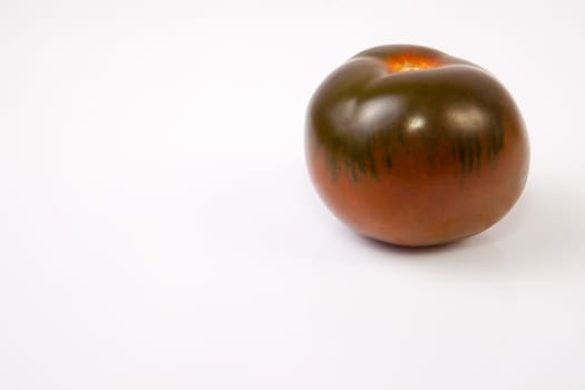 One dark green kumato tomatoe. Isolated over white background
