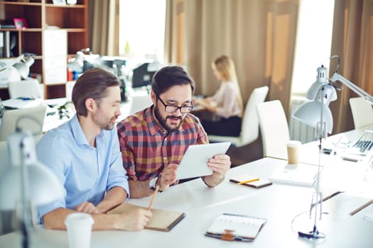 Two male employees with touchpad discussing data