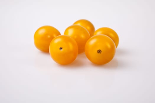 Yellow shiny cherry tomatoes. Isolated over white background
