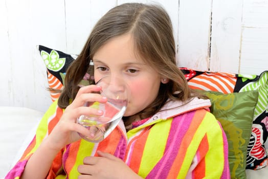 a sick girl drinking a glass of water in her bed