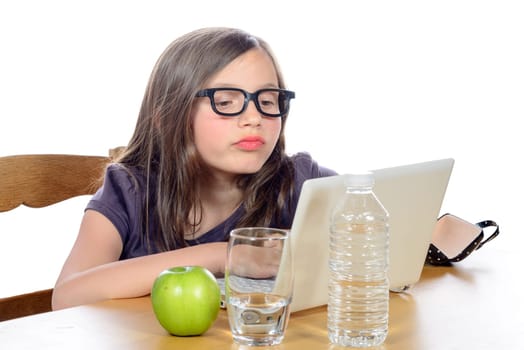 a little girl doing her homework on her computer on white