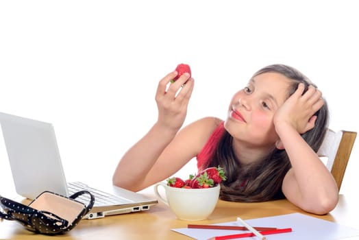 a little girl eating a strawberry on her desk