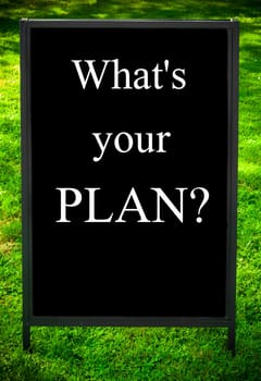 WHAT'S YOUR PLAN?  message on sidewalk blackboard sign against green grass background. Copy Space available. Concept image