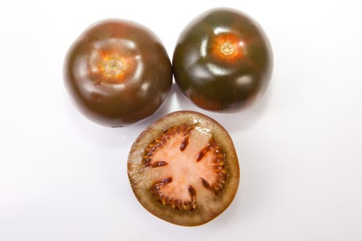 Dark green kumato tomatoes, whole and sliced. Isolated over white background