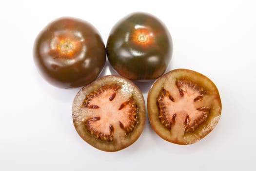 Dark green kumato tomatoes, whole and sliced. Isolated over white background