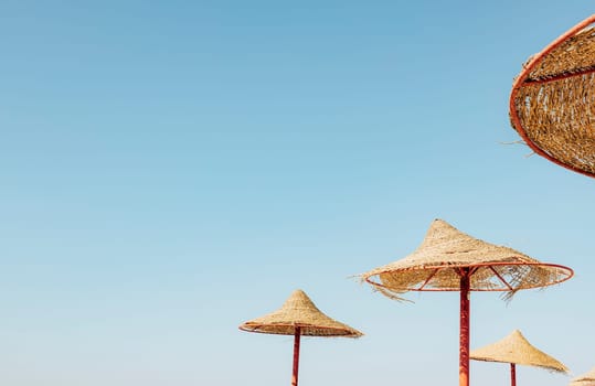 Looking up at wooden straw umbrella or thatched hut from below against beautiful cloudy blue sky view on tropical Egypt beach. Summer or winter holiday concept. Egyptian resort. High quality photo