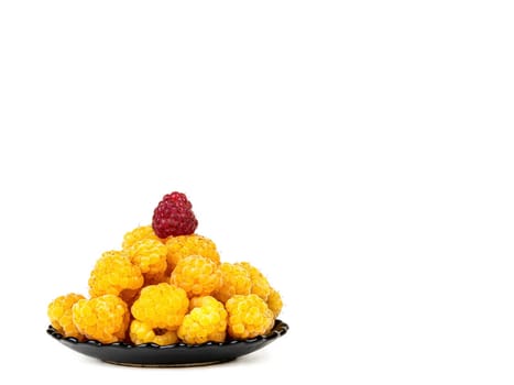 Berries of yellow and red raspberries in a black plate on a white background. Yellow raspberries. Fruit berries. Harvesting. Fruit dessert. Healthy eating. White background. Shop window.