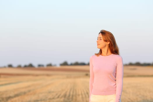 Woman contemplating views in a harvested field