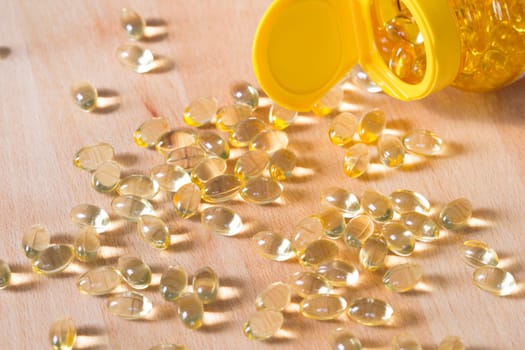 Fish oil omega pills spilled from an apothecary plastic bottle.