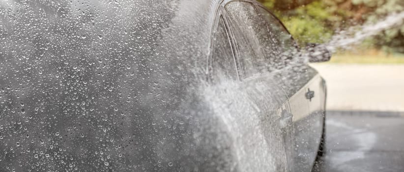 Carwash background, drops of water on the left (place for text) gradient to photo of water and shampoo spray, silver car side.