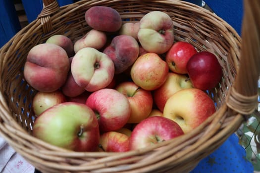wicker basket with ripe fruits, apples and nectarines