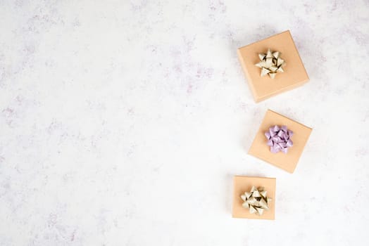 Little gift boxes on a textured light colored background, empty copy space for text, christmas season
