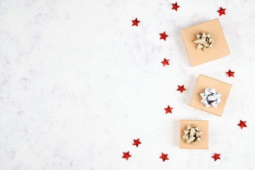 Little gift boxes on a textured light colored background, empty copy space for text, christmas season