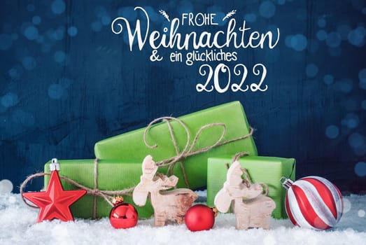German Calligraphy Frohe Weihnachten Und Ein Glueckliches 2022 Means Merry Christmas And A Happy 2022. Green Christmas Present With Decoration Like Red Ball And Reindeer And Bokeh Effect