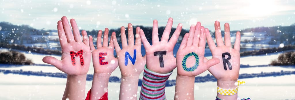 Children Hands Building Colorful English Word Mentor. Snowy Winter Background With Snowflakes
