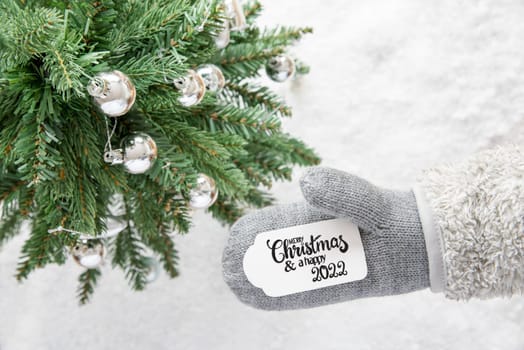 Glove With Label With English Calligraphy Merry Christmas And Happy 2022. Christmas Tree With Silver Ball Ornament And Snow