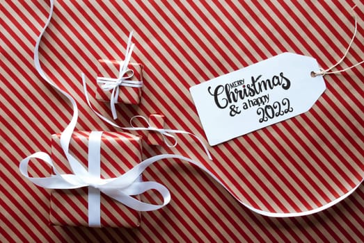 Label With English Text Merry Christmas And Happy 2022. Gifts And Presents On Red And White Wrapping Paper