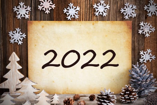 Old Paper With Text 2022. Christmas Decoration Like Tree, Fir Cone And Snowflakes. Brown Wooden Background
