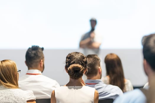 Male speaker giving a talk in conference hall at business event. Audience at the conference hall. Business and Entrepreneurship concept. Focus on unrecognizable people in audience.