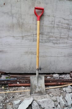 shovel leaned against the wall at a construction site
