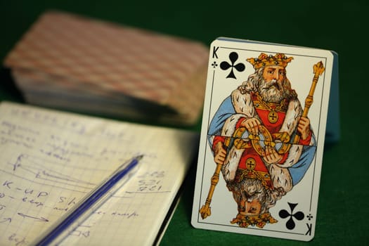 king of cross, deck of cards, paper with notes on a green cloth, card game for money, still life