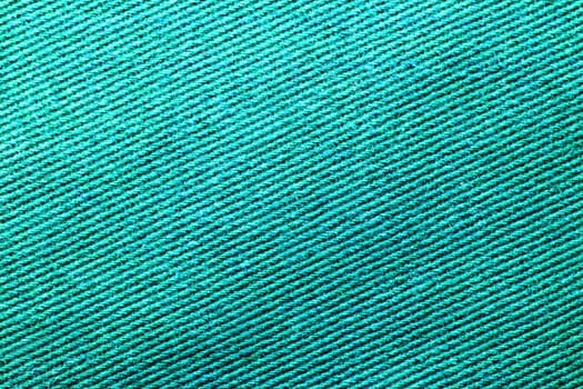 Green fabric texture. Close-up of a turquoise seamless pattern for textile, bags or other garments. Macro.