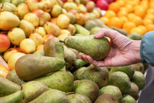 Hands of a woman choosing pear at fruit and vegetable market