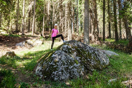 Happy little girl on the top of big rock in the forest. Adventure in nature.