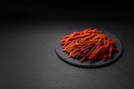 Jerky, dried fish in the form of sticks with salt, spices and herbs on a dark concrete background