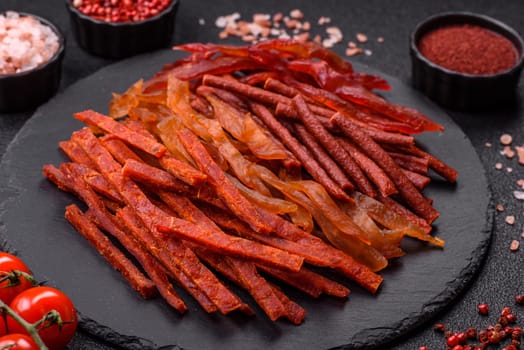 Jerky, dried fish in the form of sticks with salt, spices and herbs on a dark concrete background