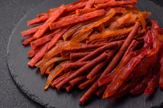 Jerky, dried fish in the form of sticks with salt, spices and herbs on a dark concrete background