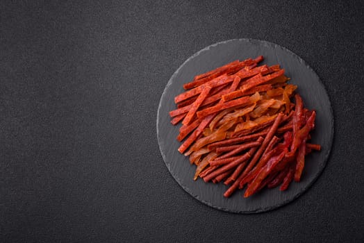 Jerky, dried fish in the form of sticks with salt, spices and herbs on a dark concrete background