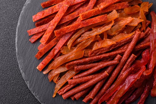 Jerky, dried fish in the form of sticks with salt, spices and herbs on a dark concrete background