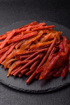 Jerky, dried fish in the form of sticks with salt, spices and herbs on a dark concrete background