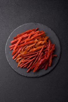 Jerky, dried fish in the form of sticks with salt, spices and herbs on a dark concrete background