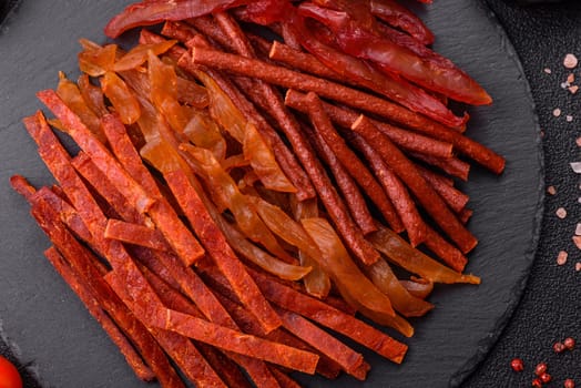 Jerky, dried fish in the form of sticks with salt, spices and herbs on a dark concrete background