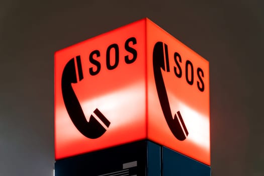 Red illuminated SOS Sign with telephone in Detail